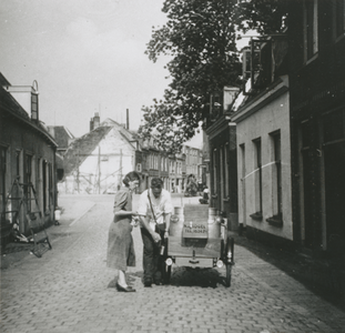 876900 Afbeelding van een melkventer met een melkkar van N. de Kogel (melkhandel, Leidsekade 81), die melk tapt voor ...